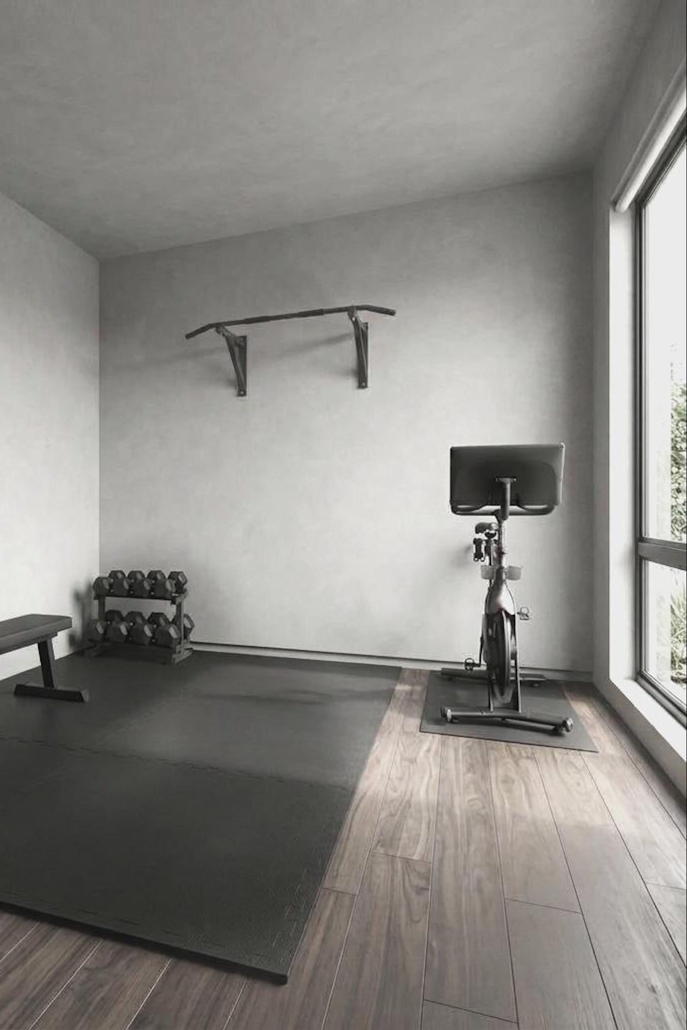 A minimalist home gym corner with a black exercise mat on dark wood flooring, a black bench.